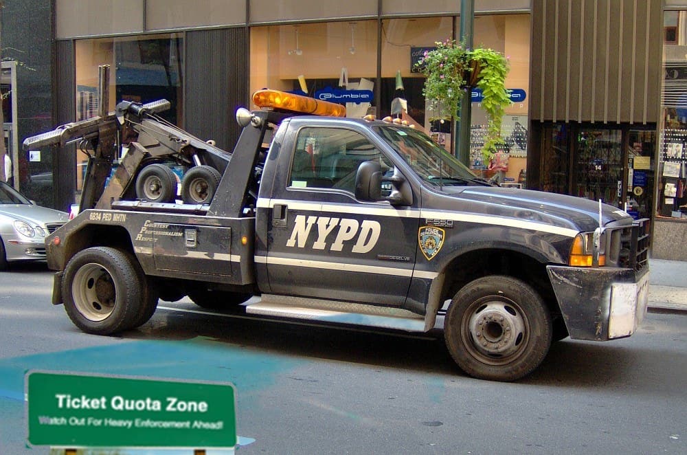 This image is a police tow truck with a parking ticket quota sign below
